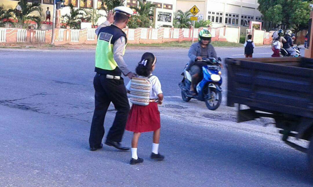 Polisi Membantu Menyebrangkan Anak Sekolah