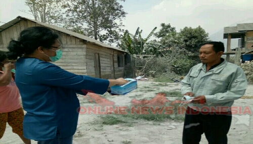 Foto : Ketua PKK Kab.Karo tampak membagikan Masker kepada warga desa Cimbang untuk mengcegah penyakit ISPA Akibat Abu Vulkanik letusan Gunung Sinabung