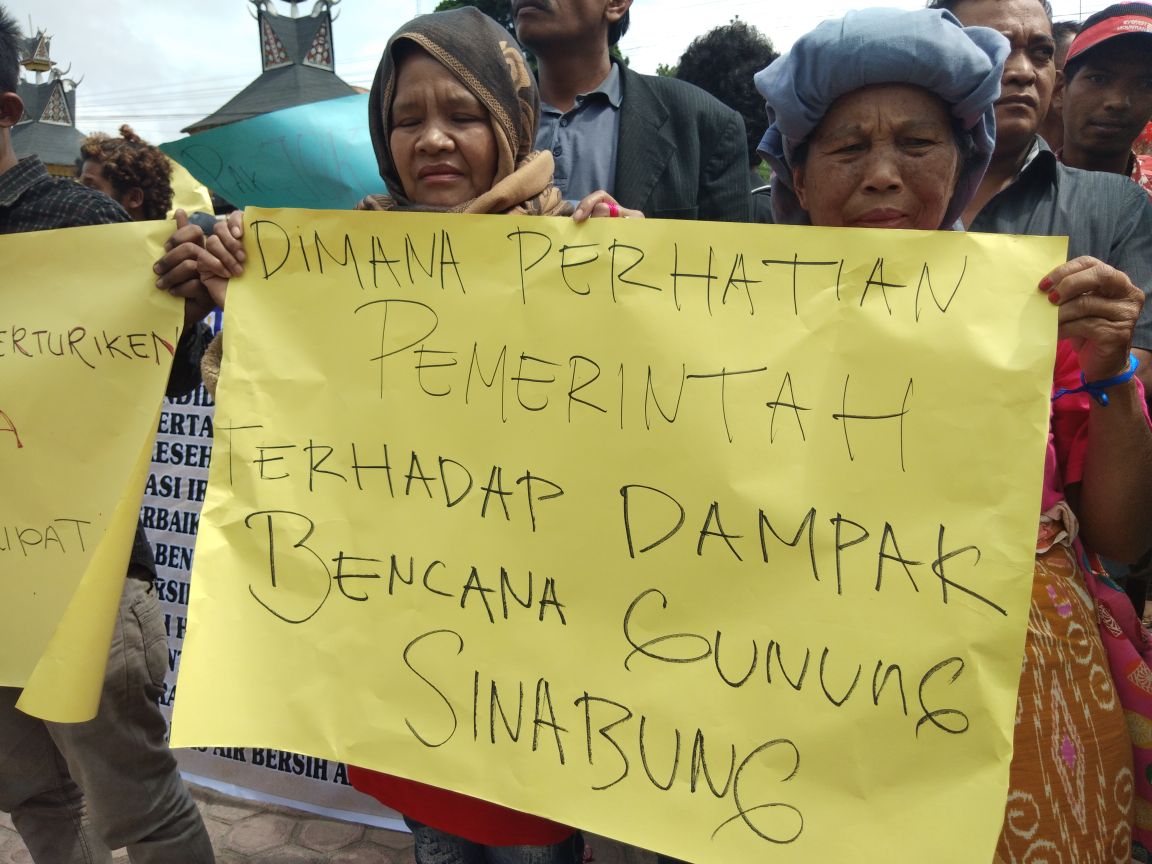 Foto : Warga Desa Batu Karang Yang berdemo di depan kantor Bupati Karo dengan membawa spanduk dari kain Dan Karton yang bertuliskan keluh kesah mereka sebagai warga yang terdampak Erupsi Gunung Sinabung