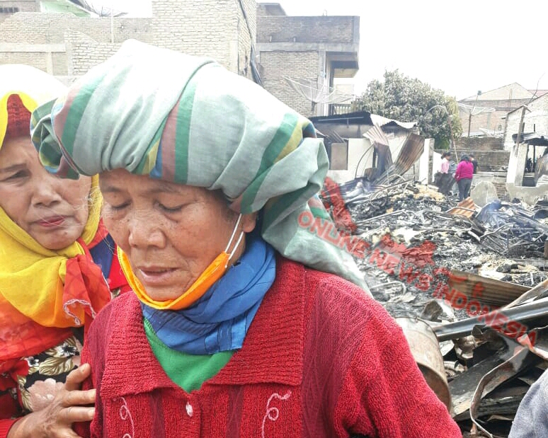 Foto : Oppung Jeremia Boru Aritonang (62), masih terlihat sedih dan trauma disaat sanak saudara menghampiri dilokasi rumah nya yang hangus terbakar