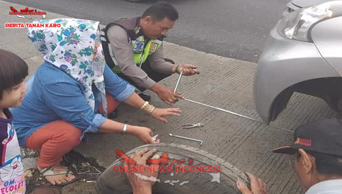 tampak Personil Poslantas Polres Karo, Bribka Sofian Damanik saat memberikan bantuan memperbaiki Ban mobil yang saat rusak di Jln Medan - Berastagi, Selasa (11 /09) 2018