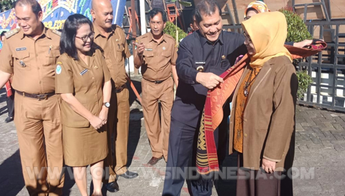 Bupati Karo saat memberikan uis nipis (ulasan Karo)  kepada ketua Tim Surveyor Akreditasi dari Kementrian Kesehatan RI  sebagai tanda tamu kehormatan