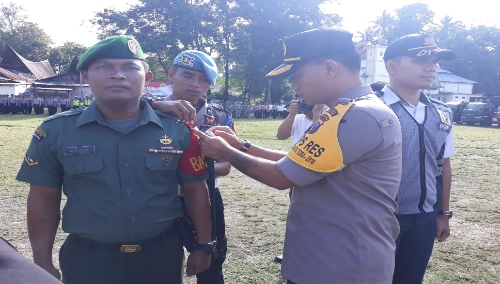 Foto : Kapolres Samosir AKBP. AGUS DAROJAD S.I.K, M.H secara simbokis  menyematkan pita operas Mantap Brata 2018 kepada salah satu personil TNI pada apel gelar pasukan OMB 2018 di tanah lapang onan lama pangururan, Jum'at (22/3)