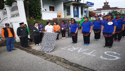 Ket foto : Ketua TP PKK Kab Karo Ny Sariati tampak melepas salah satu peserta lomba gerak jalan, Jumat (26/04) 2019