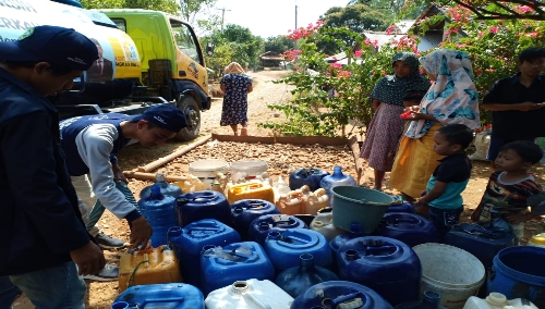 Foto : Warga Kampung Kepuh Desa Tangjung Jaya Tampak antusias antri untuk mendapatkan bantuan air bersih yang berikan Mahasiswa UNMA Yang bekerja sama dengan PDAM Labuan.