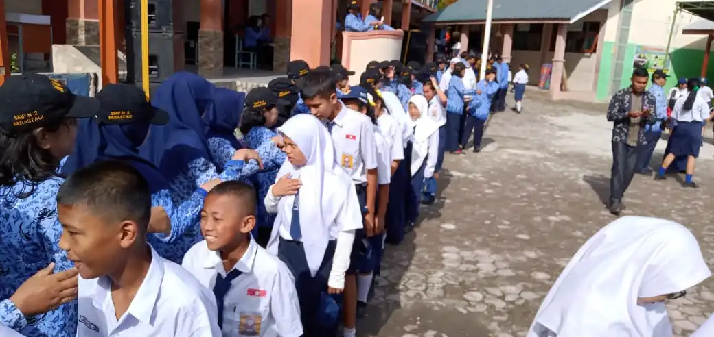 Ket foto  : Para siswa saat menyalami sekaligus memberikan ucapan selamat hari guru usai upacara bendera di halaman sekolah SMP Negeri 2 Berastagi, Senin (25/11) 2019  (Ist).