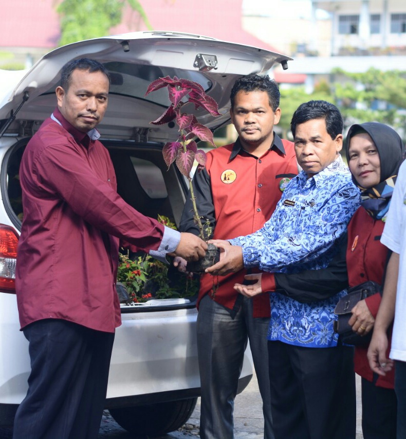 Ket foto : Perwakilan Nursianna Surbakti memberikan secara simbolis bantuan Bunga ke Camat Berastagi Mirton Ketaren S.Sos di halaman sekolah SMAN 1 Berastagi, Kamis (19/12) 2019 (Ist)