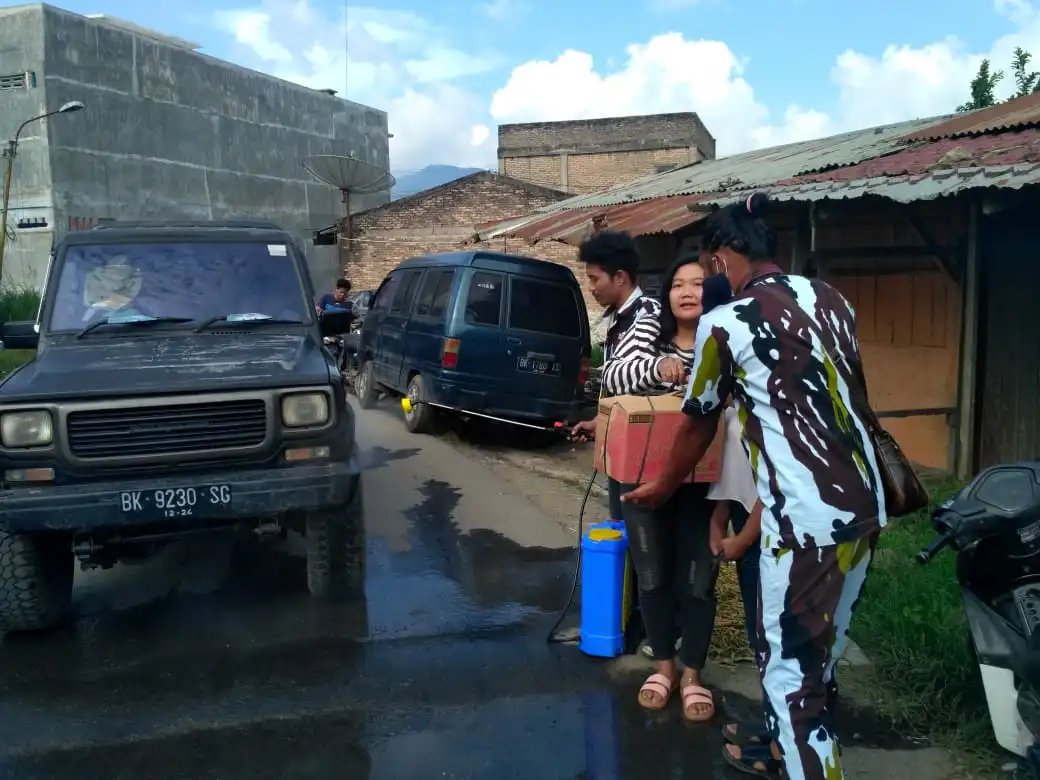 Ket foto : Disaat melakukan Aksi sosial oleh IPK Berastagi menyemprotkan Desinfektan Di jalan akses masuk ke Pasar Sayur Mayur Pajak Roga Berastagi salah satu Pemilik Usaha di Simpang Ujung Aji memberikan bantuan Obat Cairan Desinfektan kepada pengurus IPK dilokasi, Jumat (10/04) 2020 (Ist)