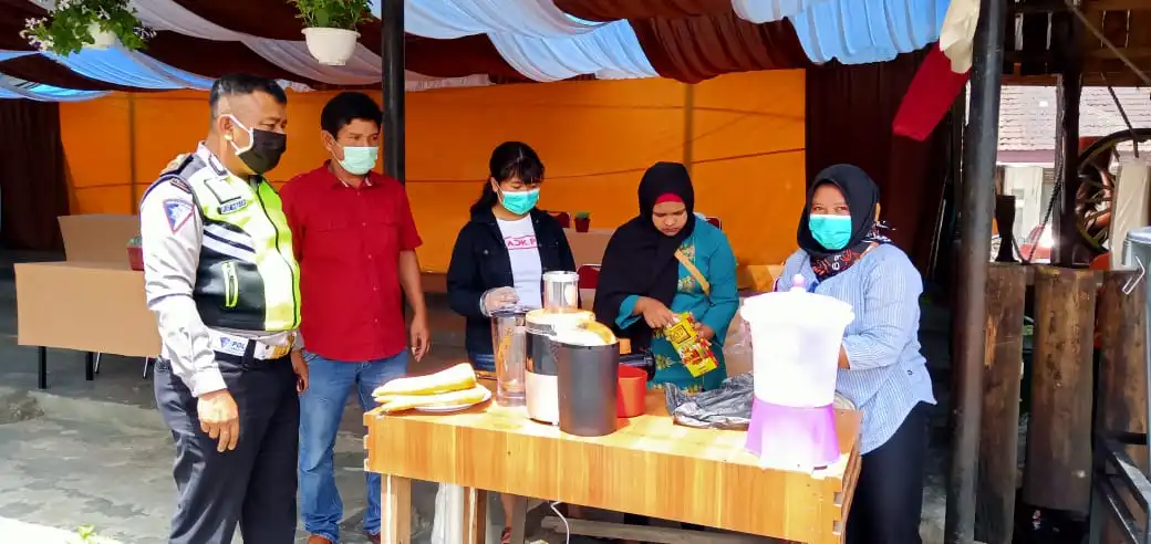 Ket foto : Kanit Lantas Berastagi Iptu Poltak Hutahean bersama Wibawa Pandia saat mengecek kesiapan dan cara pembuatan jus Wartol spesial ala Wibawa Pandia di lokasi dapur umum pasar buah di lapangan parkir taman Mejuah-juah Berastagi,Rabu (15/04) 2020 (Ist)