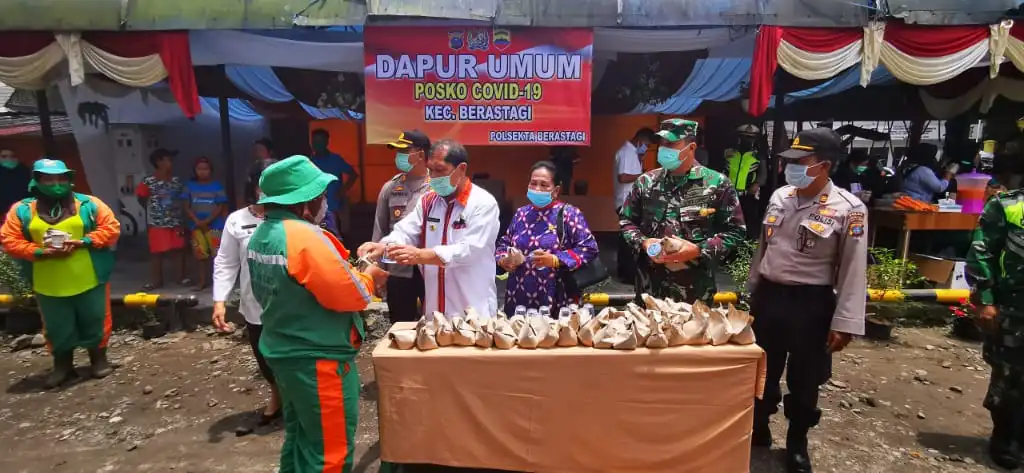Ket foto : tampak Bupati Karo Terkelin Brahmana SH membagikan Nasi bungkus dalam aksi dapur umum yang dilakukan oleh Polri di area parkir taman Mejuah juah Berastagi, Rabu (15/04) 2020 (Ist)