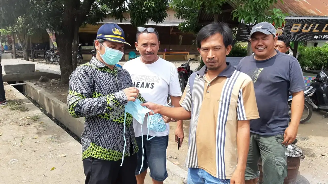 Ket foto : Camat Tigabinanga Membela Tarigan saat membagikan masker kepada warga yang sedang lalu lelang, Jumat (17/04) 2020 (Ist)