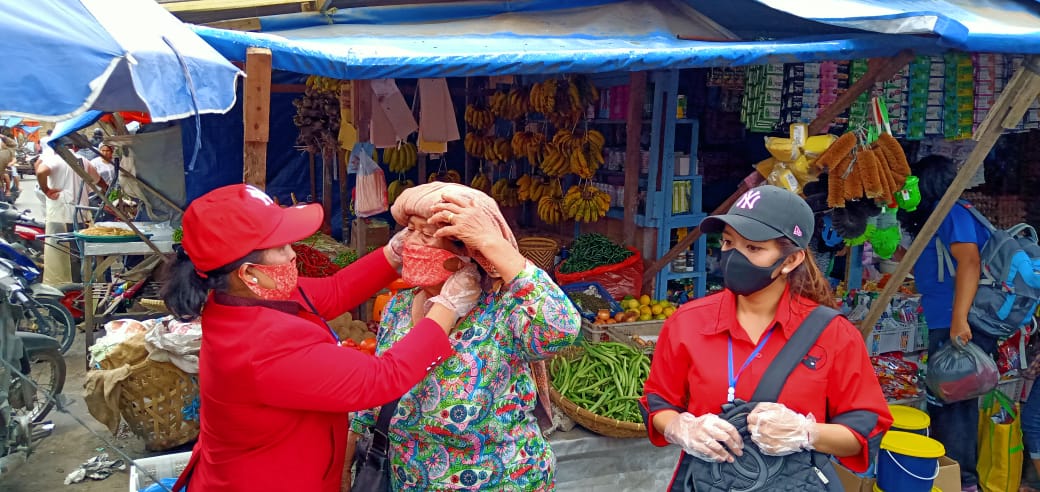 Ket foto : Ketua Fraksi PDI Perjuangan Karo Pujiati Ginting saat memasangkan masker kepada Ibu Simarmata salah satu pedagang di pusat pasar Berastagi, Sabtu (18/04) 2020 (Ist)