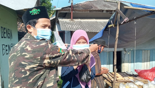 Iman, Ketua PAC Ansor Kecamatan Banjarsari (Kiri), sedang membagikan masker kepada masyarakat.